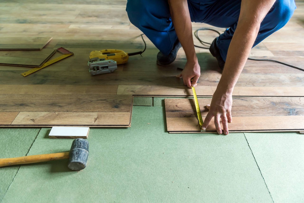 A professional using various tools to install floating hardwood floors into a space at Window Accents & Flooring near Princeton, NJ
