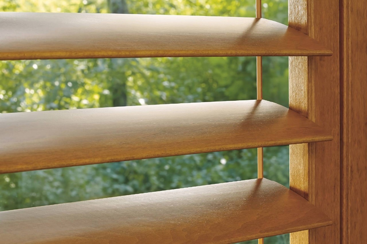 Close-up detail image of Hunter Douglas Heritance® Wood Shutters with open slats, overlooking greenery outdoors at Window Accents & Flooring near Princeton, New Jersey
